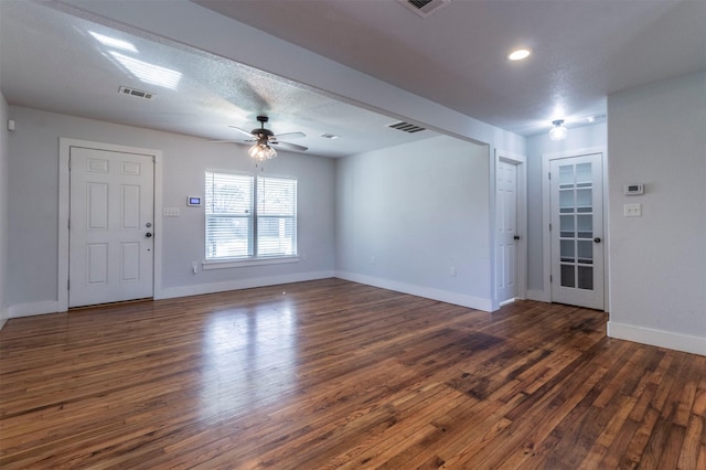 foyer entrance with visible vents, ceiling fan, dark wood-type flooring, and baseboards