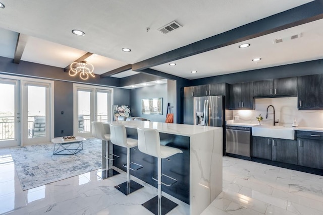 kitchen with a breakfast bar area, light countertops, marble finish floor, stainless steel appliances, and a sink