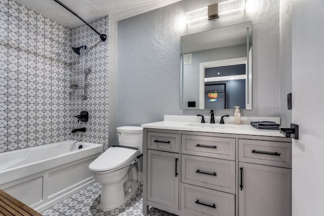 full bath with vanity, toilet, shower / tub combination, and a textured wall