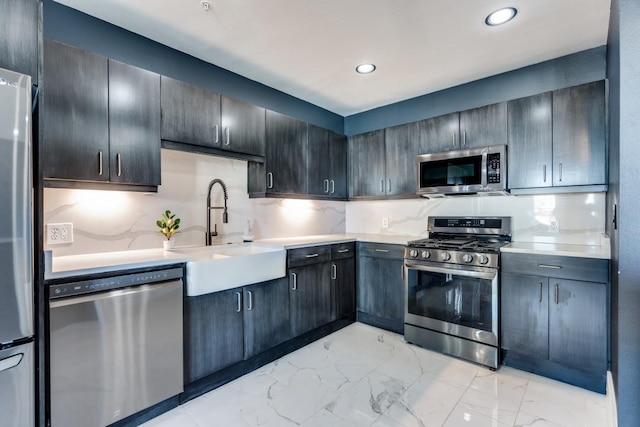 kitchen with a sink, stainless steel appliances, light countertops, marble finish floor, and backsplash