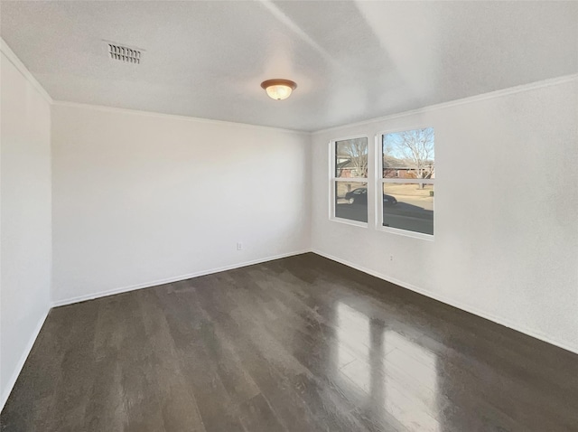 empty room featuring crown molding, baseboards, visible vents, and dark wood-style flooring