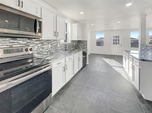 kitchen with decorative backsplash, white cabinets, appliances with stainless steel finishes, and a sink