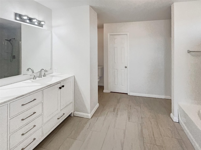 full bath with baseboards, double vanity, a sink, walk in shower, and toilet