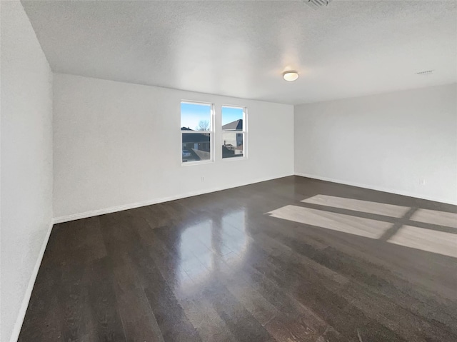 unfurnished room featuring wood finished floors, baseboards, and a textured ceiling