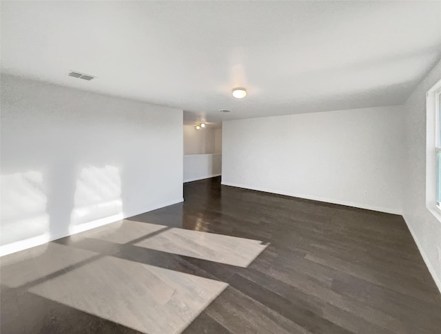 spare room with wood finished floors, visible vents, and baseboards