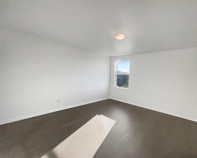 unfurnished room with baseboards and dark wood finished floors