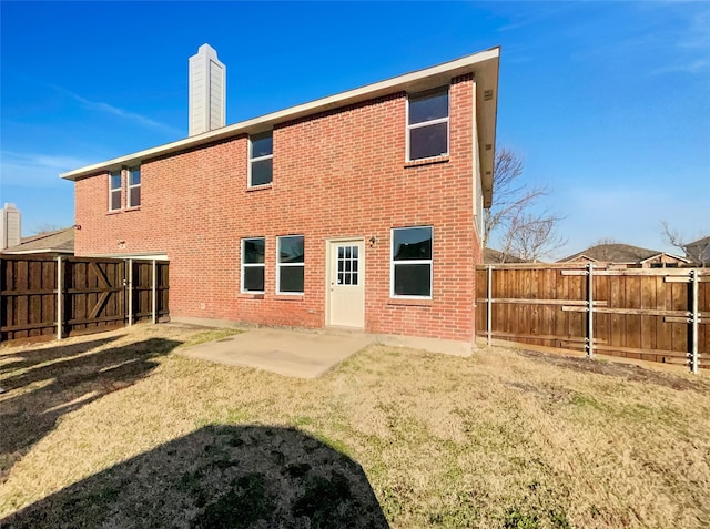 rear view of property featuring brick siding, a chimney, and a patio area