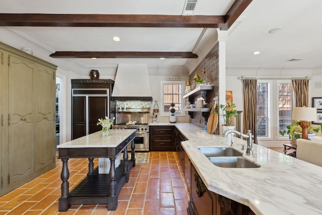 kitchen with visible vents, high quality appliances, custom range hood, beam ceiling, and a sink