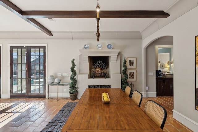 dining room featuring baseboards, beam ceiling, arched walkways, and french doors