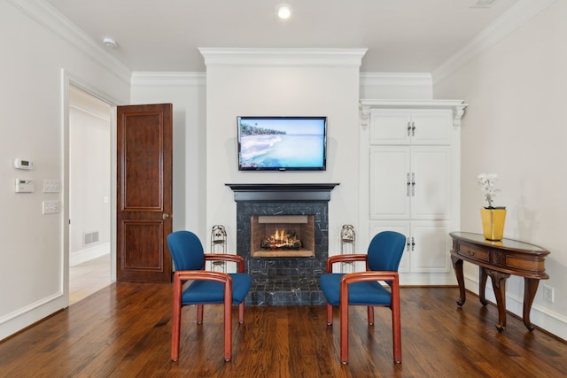 living area with crown molding, wood finished floors, visible vents, and a lit fireplace