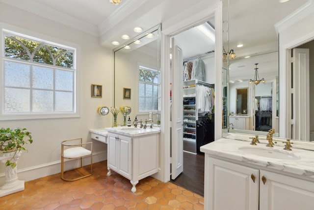 full bathroom with crown molding, a spacious closet, two vanities, and a sink