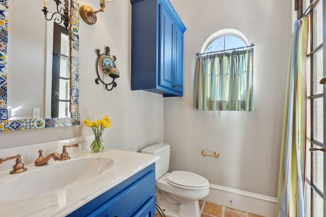 bathroom featuring vanity, toilet, baseboards, and tile patterned flooring