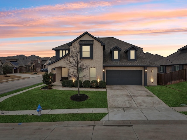 view of front of home featuring brick siding, a lawn, concrete driveway, and roof with shingles