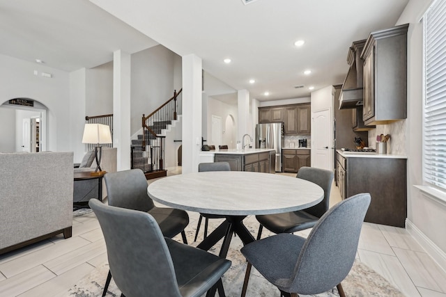 dining room with arched walkways, stairway, recessed lighting, and baseboards