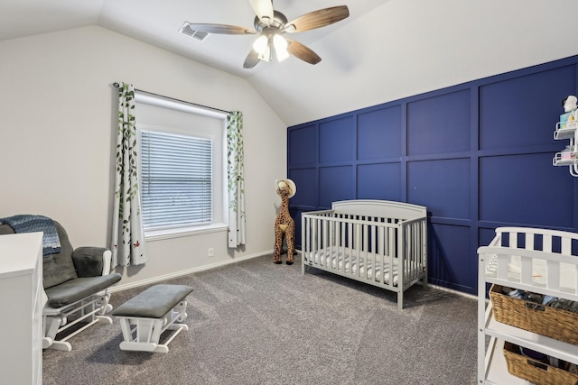 carpeted bedroom with visible vents, a ceiling fan, a nursery area, a decorative wall, and vaulted ceiling