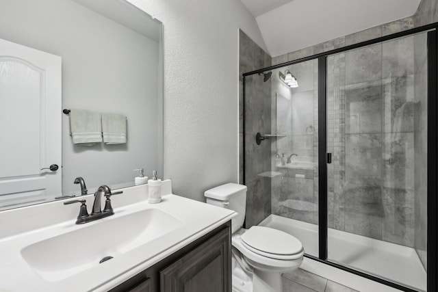 bathroom with toilet, a stall shower, a textured wall, tile patterned floors, and vanity