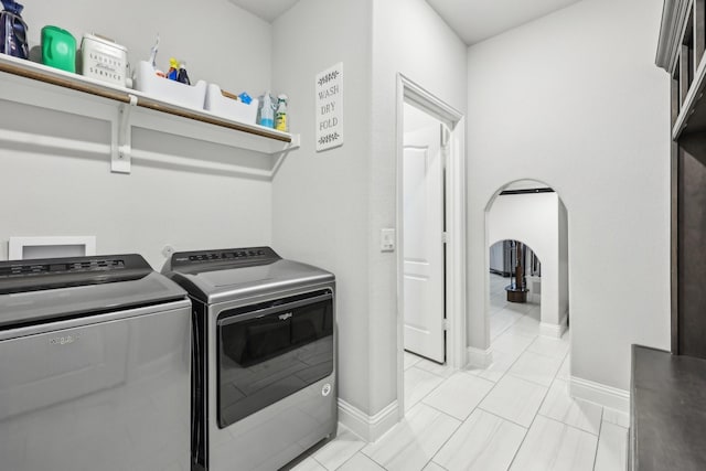 washroom featuring baseboards, arched walkways, independent washer and dryer, and laundry area