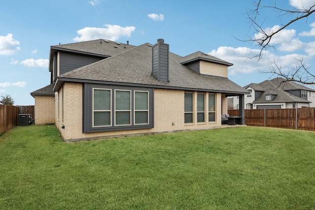 rear view of property featuring brick siding, a fenced backyard, and a yard