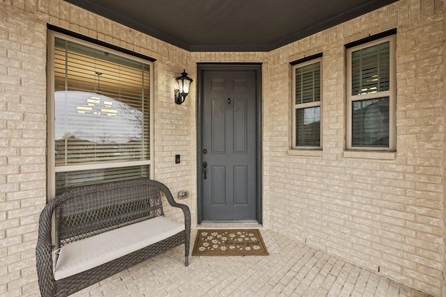 doorway to property featuring brick siding and a porch