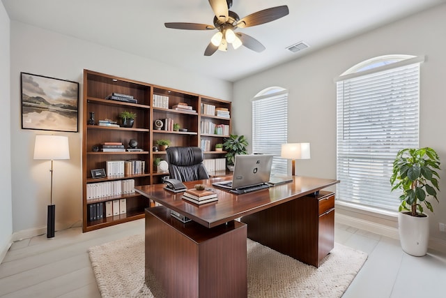 office area with a wealth of natural light, visible vents, baseboards, and a ceiling fan