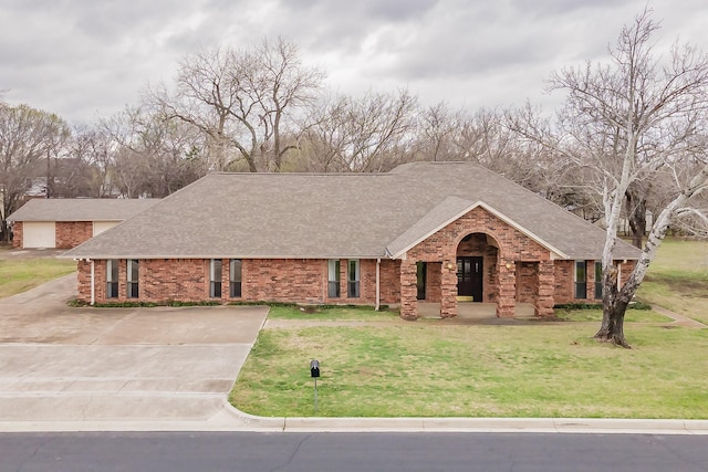 ranch-style home with brick siding, driveway, a shingled roof, and a front lawn