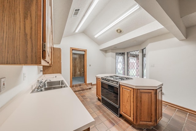 kitchen with visible vents, a sink, gas stove, brown cabinetry, and lofted ceiling