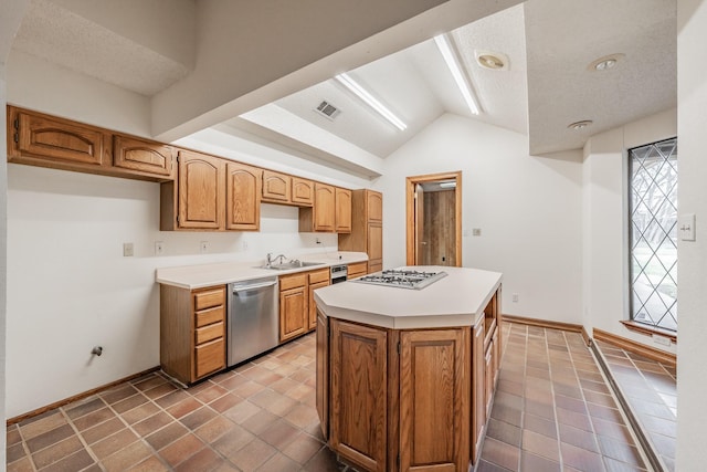 kitchen featuring visible vents, a center island, stainless steel appliances, light countertops, and vaulted ceiling