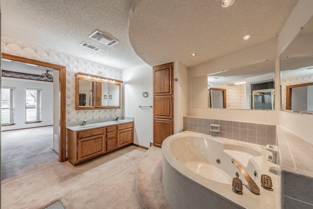 bathroom featuring a sink, visible vents, a textured ceiling, and a tub with jets