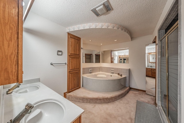 full bath featuring visible vents, a stall shower, a sink, a textured ceiling, and double vanity