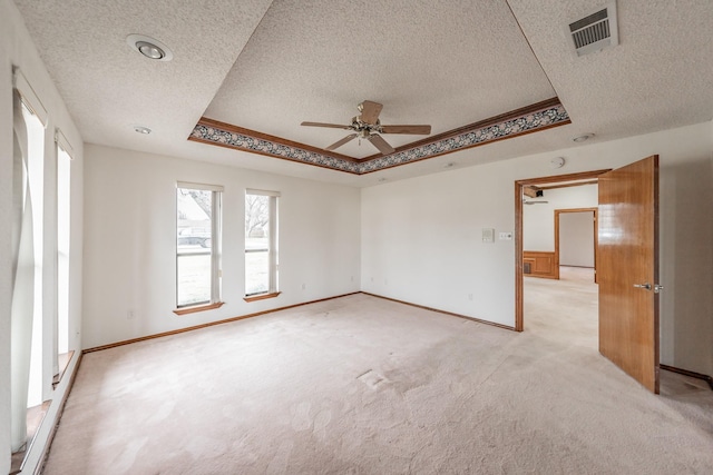 unfurnished room featuring visible vents, a raised ceiling, light colored carpet, and baseboards