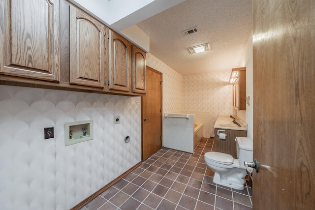 bathroom featuring wallpapered walls, toilet, a garden tub, tile patterned floors, and a textured ceiling