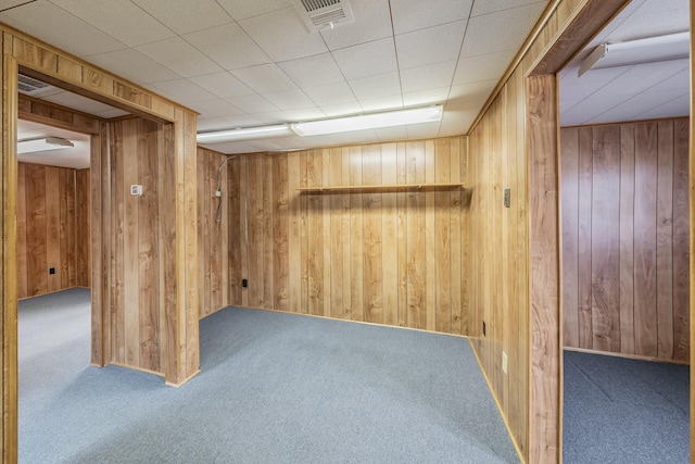 finished basement with visible vents, wood walls, and carpet floors