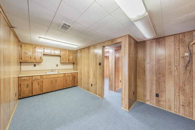 kitchen with visible vents, a sink, carpet, wooden walls, and light countertops