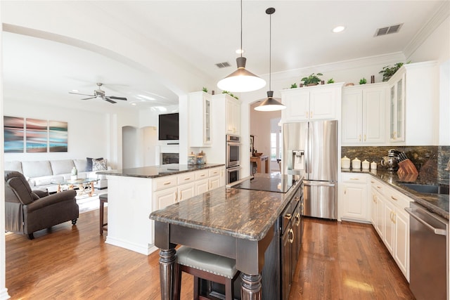 kitchen with visible vents, a kitchen bar, arched walkways, stainless steel appliances, and a sink