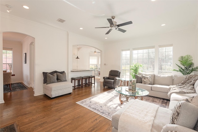 living room featuring visible vents, crown molding, recessed lighting, wood finished floors, and arched walkways