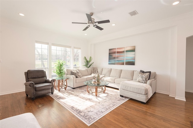 living area featuring visible vents, crown molding, baseboards, and wood finished floors