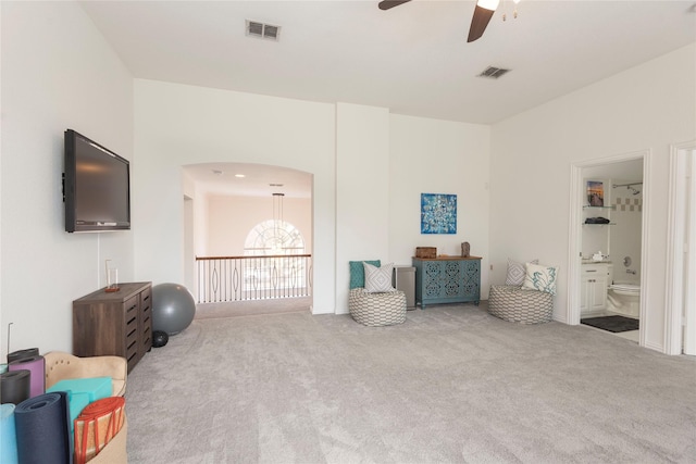 sitting room with arched walkways, visible vents, carpet flooring, and ceiling fan