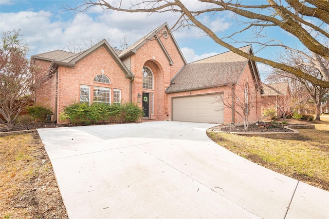 traditional-style house featuring a garage, brick siding, roof with shingles, and concrete driveway