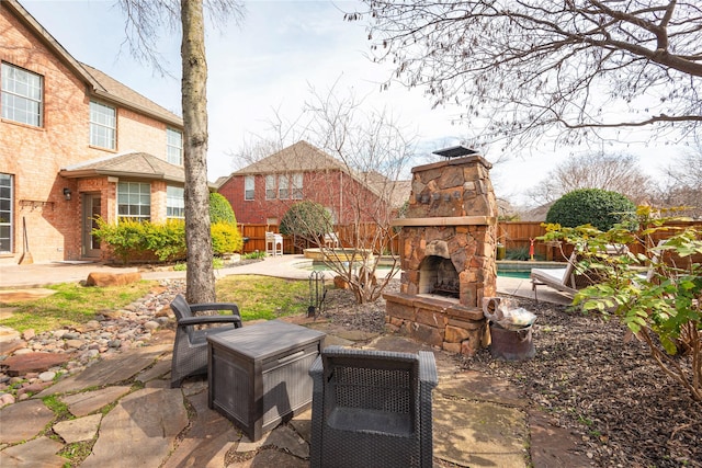 view of patio with an outdoor stone fireplace and fence