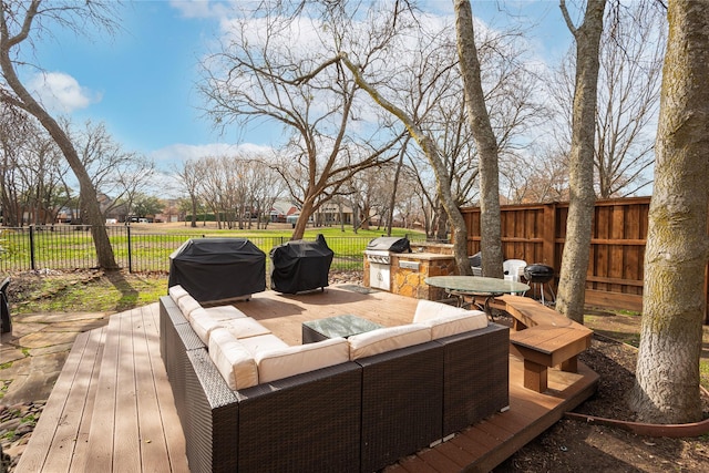 deck with an outdoor living space, grilling area, and a fenced backyard