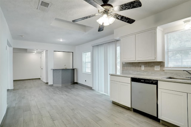 kitchen featuring visible vents, light wood finished floors, a sink, dishwasher, and backsplash