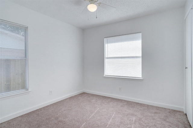 carpeted empty room featuring ceiling fan, a textured ceiling, and baseboards