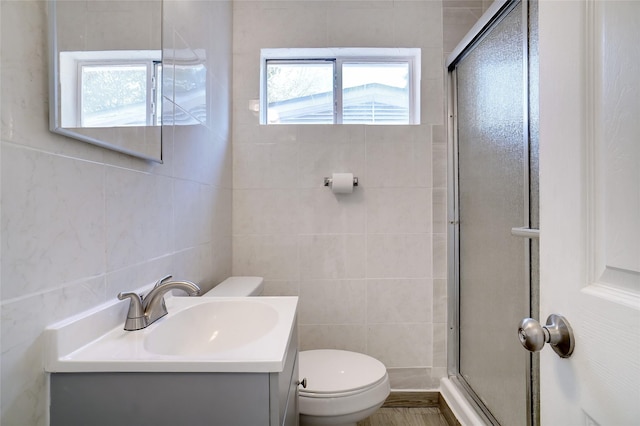 bathroom featuring a stall shower, toilet, tile walls, and vanity