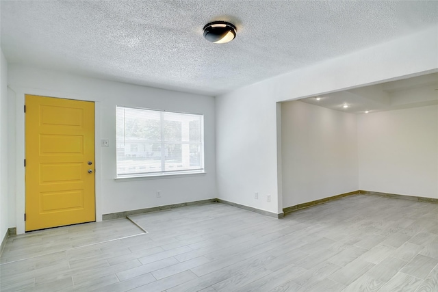 foyer with a textured ceiling, light wood-type flooring, and baseboards