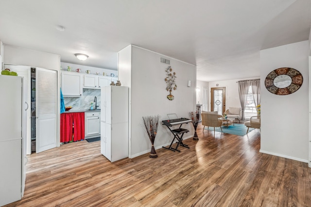 interior space featuring light wood finished floors, visible vents, baseboards, and a sink