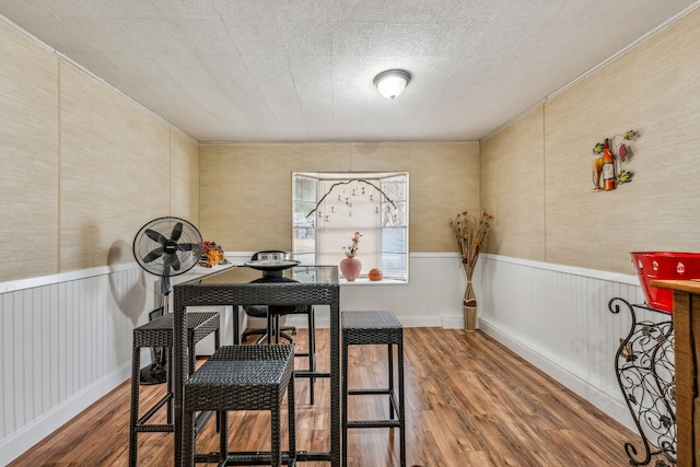 dining room with wood finished floors, a wainscoted wall, and a textured ceiling