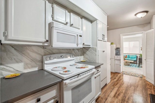 kitchen with tasteful backsplash, dark countertops, white cabinetry, white appliances, and light wood-style floors