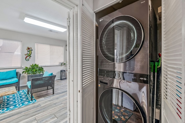 laundry area featuring laundry area, wood finished floors, and stacked washing maching and dryer