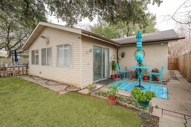 rear view of property with a patio area, a yard, a fenced backyard, and brick siding