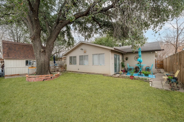 rear view of house featuring a patio area, a lawn, a shingled roof, and a fenced backyard